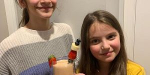 Two smiling girls showing off their fruit drink creation