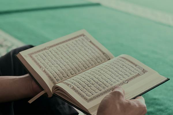 Hands holding an open book, the Quran